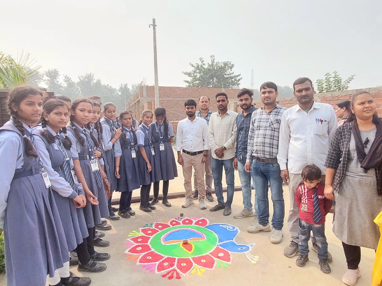 Students with peacock rangoli design